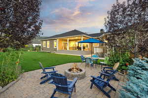 Back of house at dusk featuring a fire pit and a patio
