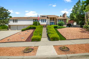 Tri-level home featuring concrete driveway, stairway, brick siding, a garage, and french doors