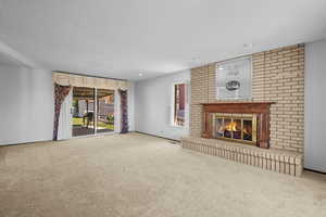 Unfurnished living room featuring carpet floors, a textured ceiling, a fireplace, and recessed lighting