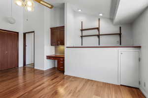 Interior space with light wood finished floors, built in desk, a towering ceiling, and ceiling fan