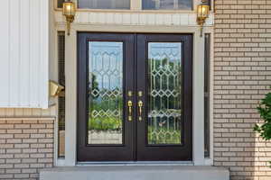 View of exterior entry featuring french doors, brick siding, and board and batten siding