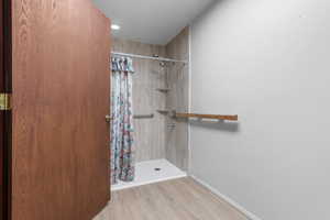 Full bath with a shower stall, wood finished floors, and recessed lighting