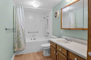 Full bath featuring shower / bath combo with shower curtain, vanity, and wood finished floors
