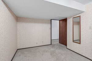 Unfurnished bedroom with wallpapered walls and carpet