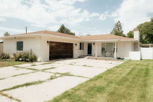 Ranch-style house with a garage, a chimney, a porch, brick siding, and driveway