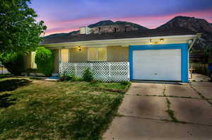 Ranch-style home featuring a mountain view, concrete driveway, a garage, and a front yard