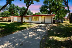 Single story home featuring a garage, concrete driveway, and a yard