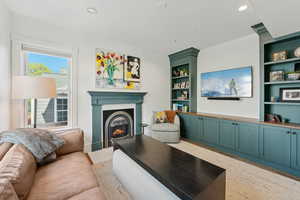Living area with a fireplace with flush hearth with a gas log, recessed lighting, and built in shelves