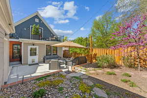 Back of house with upper balcony, an outdoor living space, a fenced backyard, and a patio