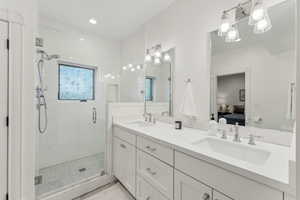 Main floor ensuite bathroom featuring double vanity with quartz countertops, white subway tile and marble floors, and recessed lighting