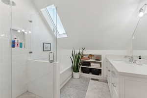 Shared full bath featuring a skylight, vanity with quartz counters, separate shower & tub, and marble tile patterned flooring