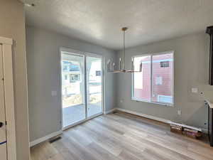 Unfurnished dining area with light wood-style floors and a textured ceiling