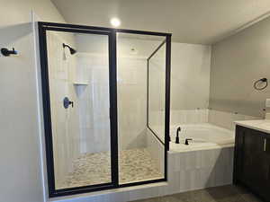 Bathroom with vanity, a garden tub, a shower stall, tile patterned floors, and a textured ceiling