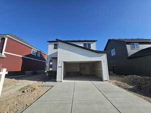 View of front of property featuring concrete driveway and an attached garage