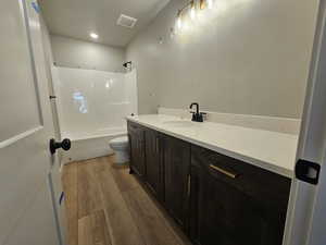 Bathroom featuring vanity, wood finished floors, bathtub / shower combination, and recessed lighting