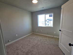 Spare room with a textured ceiling and light carpet