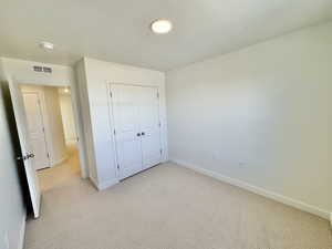 Unfurnished bedroom featuring light carpet, a closet, and a textured ceiling