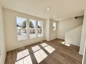 Unfurnished living room with plenty of natural light, wood finished floors, recessed lighting, and stairs