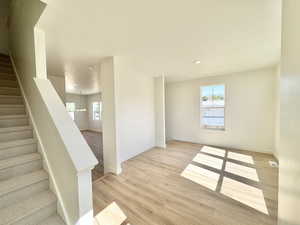 Stairway with healthy amount of natural light, wood finished floors, and recessed lighting