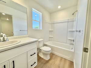 Bathroom featuring wood finished floors, vanity, bathtub / shower combination, and recessed lighting
