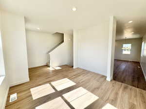 Unfurnished living room featuring wood finished floors, recessed lighting, stairs, and a chandelier