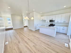 Kitchen with stainless steel appliances, light countertops, light wood-style flooring, a chandelier, and recessed lighting