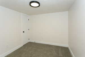 Spare room featuring dark colored carpet and a textured ceiling