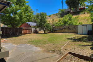Fenced backyard featuring a shed and a patio area