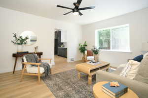 Living area with light wood-type flooring and a ceiling fan