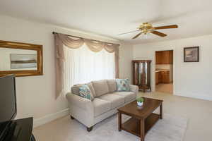 Digitally Staged: Living room with ceiling fan and light carpet