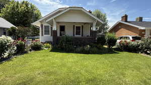 View of front of home featuring a front lawn, a porch, and stone siding