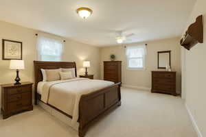Digitally Staged: Bedroom featuring light colored carpet and a ceiling fan