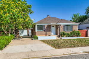 Bungalow featuring brick siding, driveway, a garage, and an outbuilding
