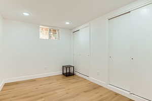 Unfurnished bedroom with light wood-style flooring, recessed lighting, and multiple closets