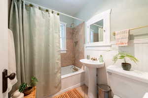 Bathroom featuring shower / bath combo with shower curtain, tile patterned floors, and a wainscoted wall