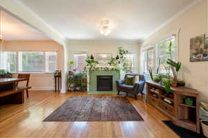 Living room with a tile fireplace, wood finished floors, crown molding, and a chandelier