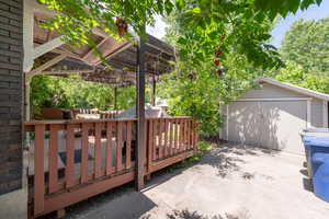 Wooden deck featuring an outbuilding, driveway, and a pergola