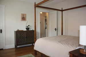 Bedroom with dark wood finished floors and baseboards