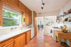 Kitchen with white appliances, light countertops, light tile patterned floors, open shelves, and a chandelier