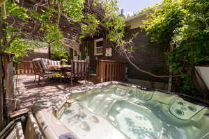 View of patio with a hot tub, a deck, and outdoor dining area