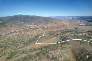 Aerial view of property and surrounding area with property parcel outlined and a mountain backdrop