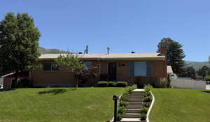 Ranch-style house with a mountain view, a chimney, stairs, and brick siding