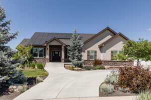 View of front of home featuring stone siding, stucco siding, and roof mounted solar panels