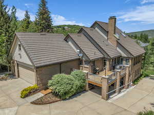 Rear view of property featuring brick siding, concrete driveway, a wooden deck, and a chimney