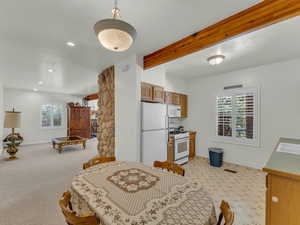 Dining space featuring healthy amount of natural light, beamed ceiling, light carpet, and recessed lighting