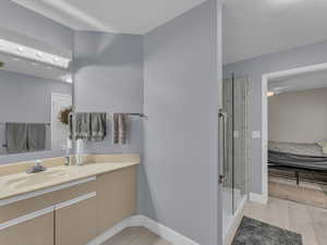 Bathroom with vanity, a shower stall, connected bathroom, and wood finished floors