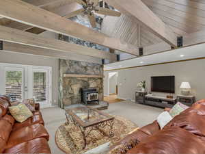 Living area featuring light carpet, a wood stove, a wood ceiling with exposed beams, high vaulted ceiling, and french doors