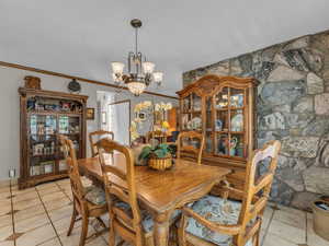 Dining space featuring a chandelier, light tile patterned floors, and crown molding