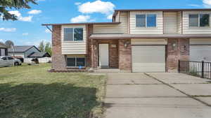 View of front of house featuring concrete driveway, brick siding, and an attached garage
