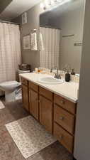 Full bath with vanity, a textured ceiling, and stone finish flooring